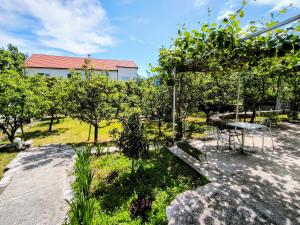 a garden with a table and trees and a building at Apartments and Rooms Minex in Trebinje