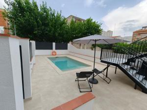 a patio with a swimming pool and an umbrella at Hostal Manel in Pineda de Mar
