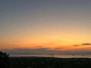 a sunset over a city and the ocean at Golden Hour on the Hill in Aegina +14 photos