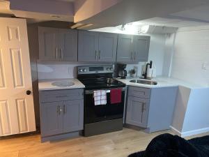 a kitchen with gray cabinets and a stove top oven at Private basement apartment with separate entrance in Yonkers