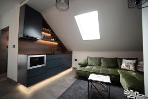 a living room with a green couch and a kitchen at JelenaR in Novi Sad