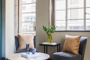 a living room with two chairs and a table with a vase at Stylish 1BR in Durban