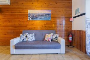 a couch in a room with a wooden wall at Dimora Levante - Pool & Tennis in Noicattaro