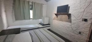 a room with a bed and a tv on a wall at Pousada Tia Lucia in Saquarema