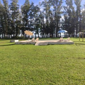 two benches with umbrellas in a grass field at Complejos EG in San Miguel del Monte