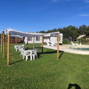a group of tables and chairs under a canopy next to a pool at Complejos EG in San Miguel del Monte