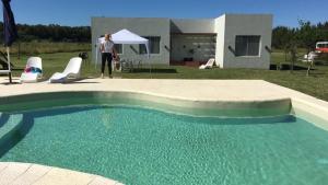 a woman standing next to a swimming pool next to a house at Complejos EG in San Miguel del Monte +2 photos