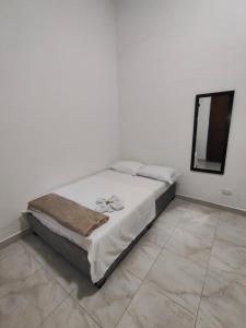 a bed in a white room with a mirror at Hospedaje Monasterio in Buga