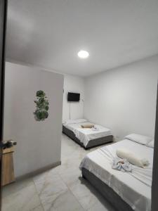 a bedroom with two beds and a flat screen tv at Hospedaje Monasterio in Buga