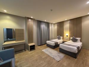 a hotel room with two beds and a flat screen tv at شقق السعادة سويت للشقق المخدومة - Saada Suites Serviced Apartments in Riyadh