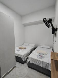 two beds in a white room with a microphone at Hospedaje Monasterio in Buga