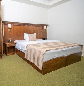 ein Schlafzimmer mit einem großen Bett mit hölzernem Kopfteil in der Unterkunft Insfra Hotel in Khatīma