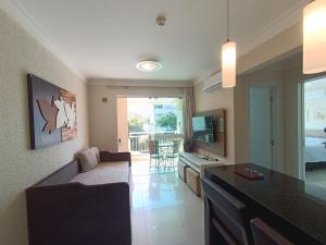 a living room with a couch and a kitchen with a television at Bombinhas Summer Beach in Bombinhas