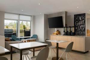 a living room with tables and chairs and a tv at TownePlace Suites by Marriott Seekonk in Seekonk