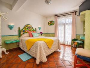 a bedroom with a large bed with a yellow blanket at Hotel Quinta Bella in Tula de Allende