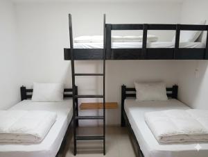 a room with two bunk beds with white sheets at Apartaestudio amoblado Aeropuerto PIMSA bombona in Malambo