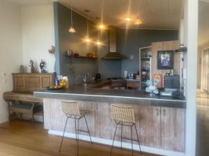 a kitchen with a bar with two stools at Stone Store Lodge in Kerikeri