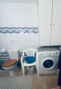 a bathroom with a toilet and a chair and a washing machine at Second Home Ierissos in Ierissos