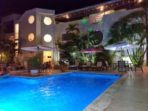 a swimming pool at night with tables and umbrellas at Hotel Don Andres in Sosúa