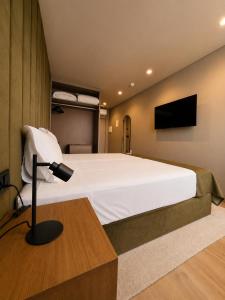 a bedroom with a large white bed and a lamp at INOTEL Paços de Ferreira in Paços de Ferreira