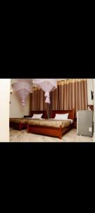 a bedroom with two beds with pink curtains at Meraki Palate in Entebbe