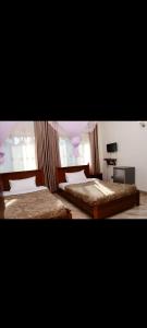 a bedroom with two beds and a television in it at Meraki Palate in Entebbe