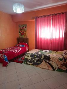 two beds in a room with red walls at appartement 3 gare tgv in Kenitra