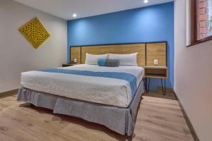 ein Schlafzimmer mit einem großen Bett und einer blauen Wand in der Unterkunft Continental Mexicano in Mexiko-Stadt