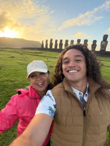 a man and a woman posing in front of a statue at Cabañas Anariki in Hanga Roa