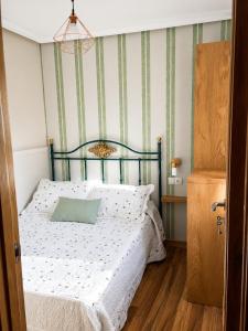 a bedroom with a bed with a green striped wall at La casita "A de Naval" in Pontevedra