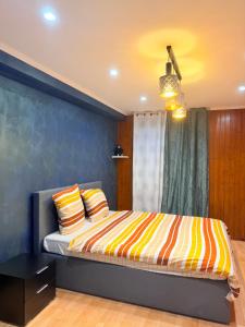 a bedroom with a bed with a colorful striped blanket at Maison privative SPA Jacuzzi Sauna Salle de jeux in Weitbruch