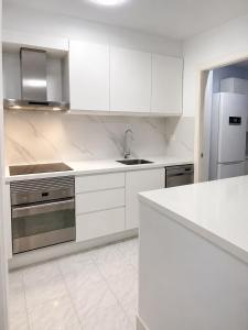 a white kitchen with a sink and a refrigerator at Verdi House in Torrevieja