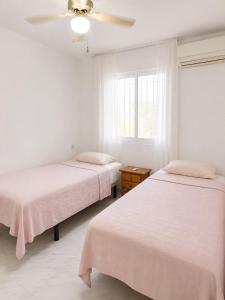 two beds in a white room with a ceiling fan at Verdi House in Torrevieja