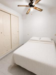 a white bedroom with a bed and a ceiling fan at Verdi House in Torrevieja