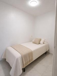 a white bedroom with a bed with white walls at Verdi House in Torrevieja