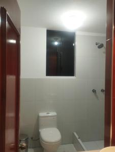 a bathroom with a toilet and a shower with a window at Alpha in Cajamarca