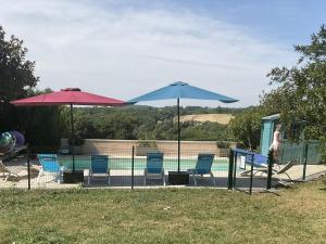 two umbrellas and chairs next to a swimming pool at Petit Vingne in Édon