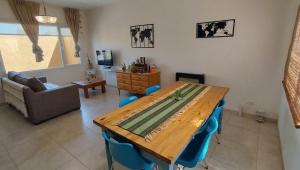 a living room with a wooden table and blue chairs at Casa Valdés in Puerto Pirámides