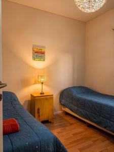 a bedroom with two beds and a table with a lamp at Casa Valdés in Puerto Pirámides