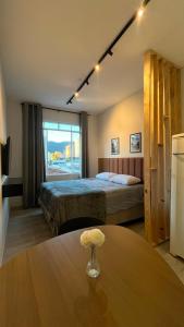 a hotel room with a bed and a table with flowers on it at Studio no Centro com VISTA PARA O CRISTO in Poços de Caldas
