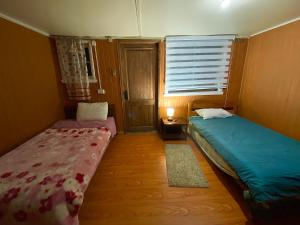 two beds in a small room with a window at Cabañas Deisy in Valdivia