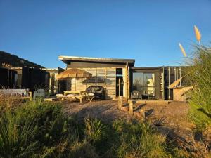 a house with a table and chairs in front of it at Rangitoto Retreat Raglan in Te Akau