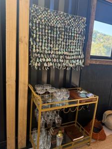 a room with a chandelier and a table with glasses at Rangitoto Retreat Raglan in Te Akau