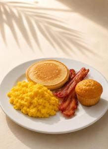 a plate of breakfast food with eggs bacon and pancakes at Hotel Tropical Inn in Tierra Bomba