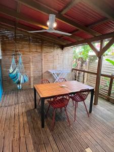 a wooden table and chairs on a deck with a hammock at an eol caraibes in Trois-Rivières