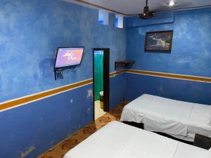 a room with two beds and a flat screen tv at HotelMariaAngela in Dzuiché +1 photo