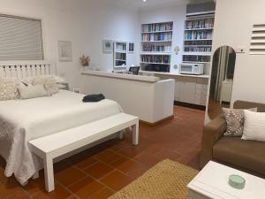 a bedroom with a bed and a couch and a kitchen at Ciara's Cottage CC'S in Illawong