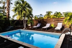 a swimming pool with two chairs and palm trees at Villa Madame in Saint Martin