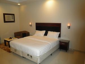 1 dormitorio con 1 cama grande y 1 mesa en مراحل للشقق المخدومة الخرج 1, en Al Kharj