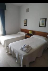 a room with two beds with towels on them at Hotel Benalua in Isla de Arosa